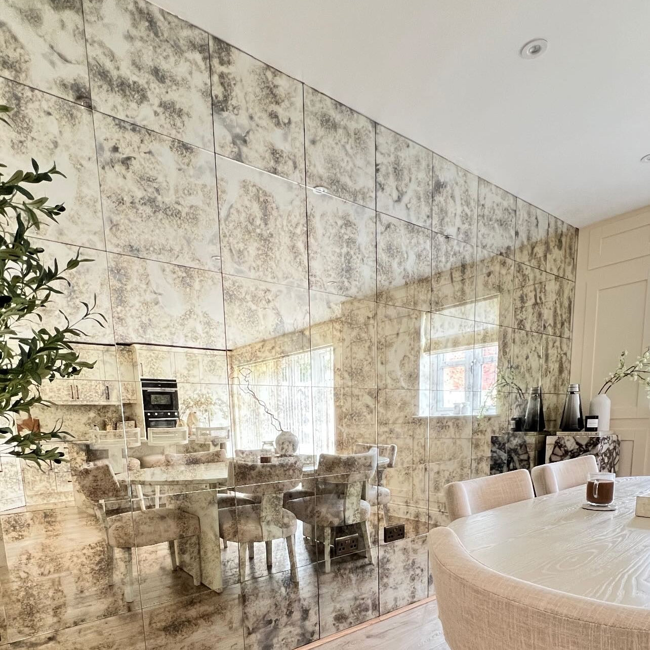 Modern interior design with reflective wall, dining table, and chairs.