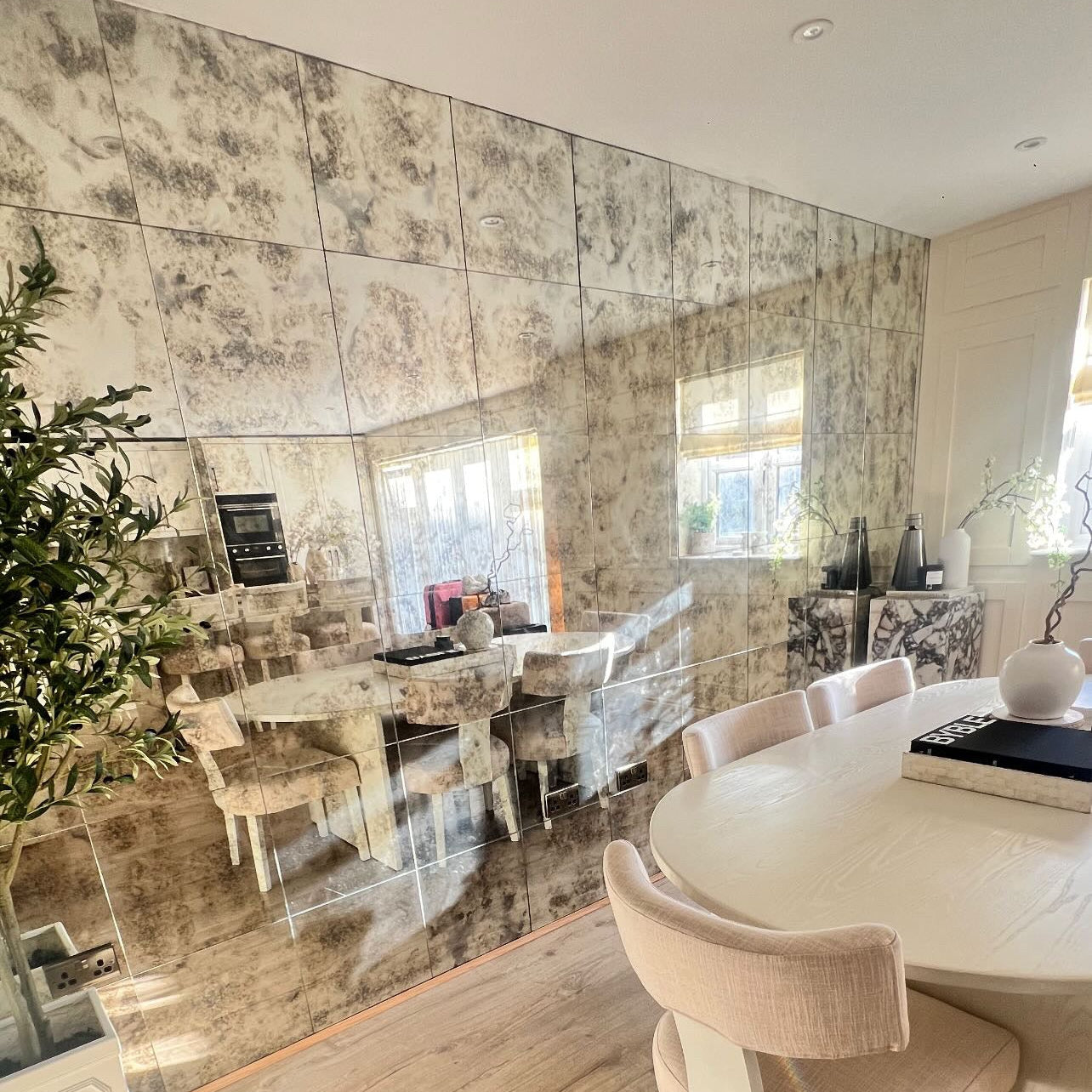 Modern dining room with large mirror on the wall, wooden floor, and round table.