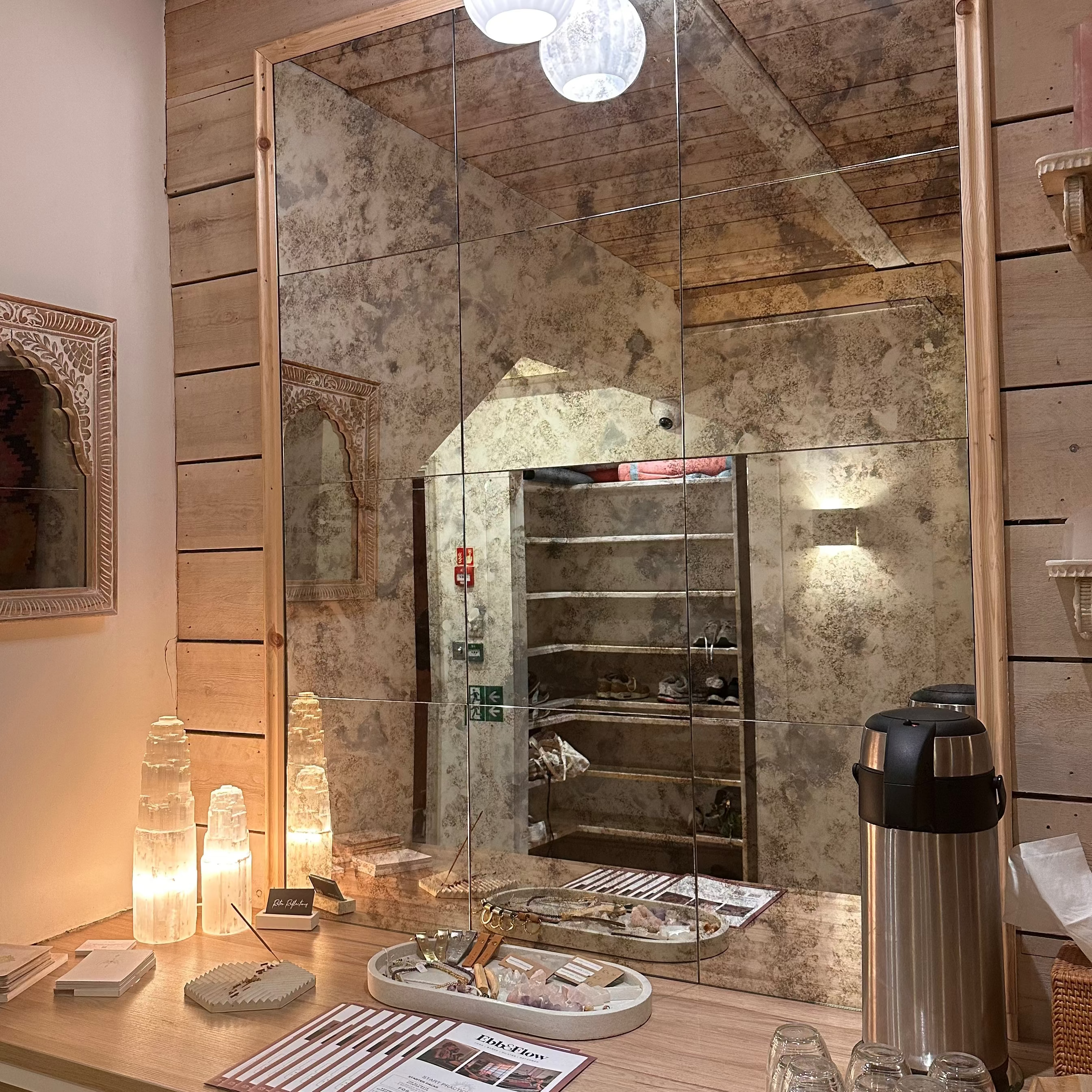 Wooden bar counter with mirror, bottles, and glasses in a rustic setting