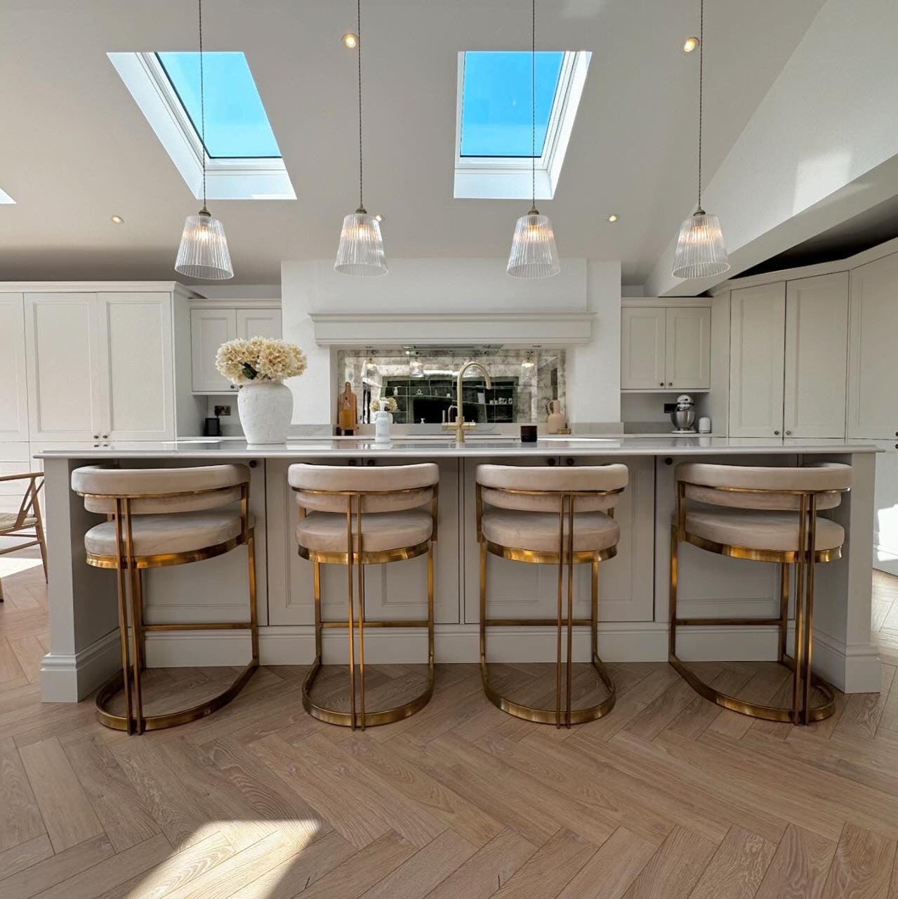 Modern kitchen with skylights, pendant lights, and bar stools.