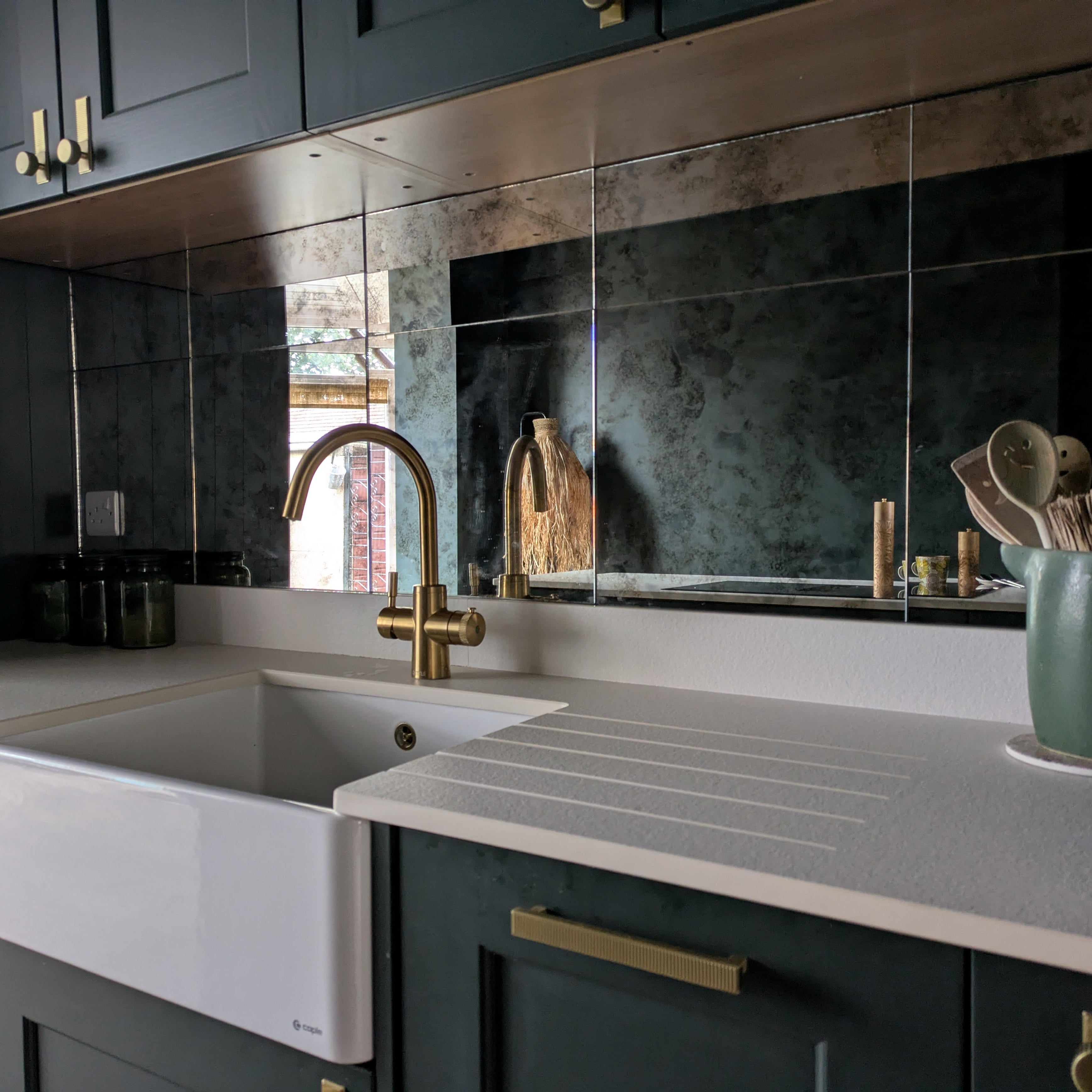 Modern kitchen with a white sink, gold faucet, and dark cabinets.