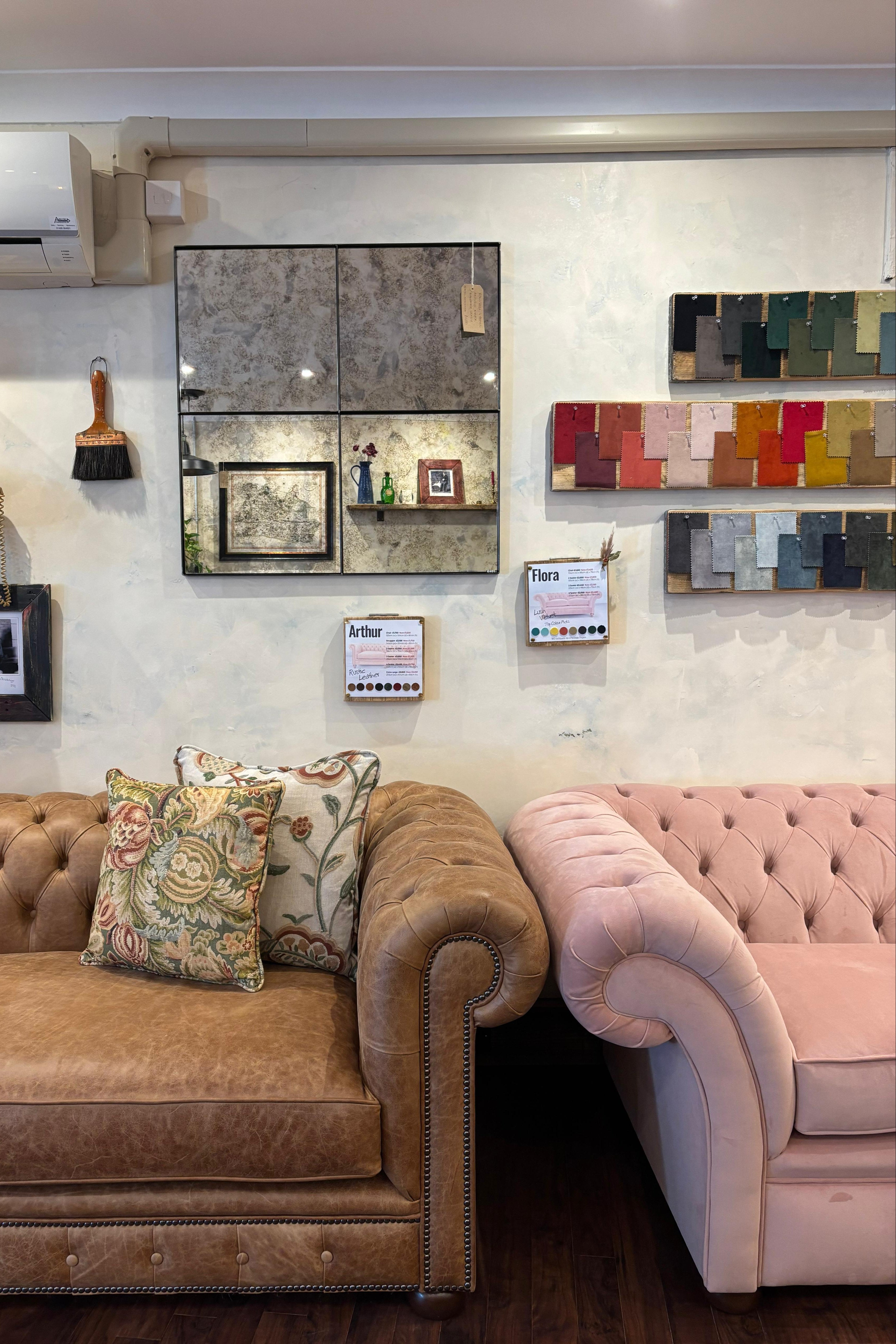 Two sofas, one brown and one pink, in a room with color swatch samples on the wall.