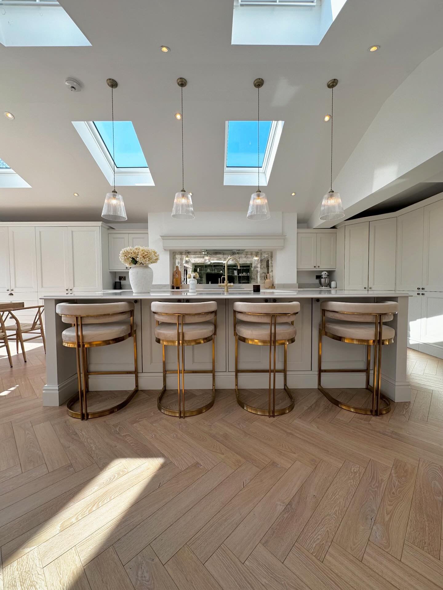 Modern kitchen with skylights, pendant lights, and bar stools.