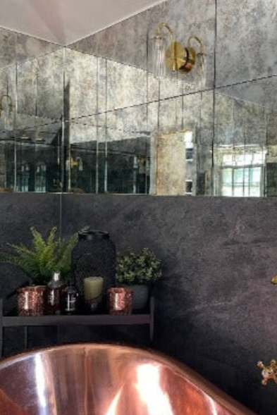 Bathroom with a copper bathtub, mirror, and decorative elements.