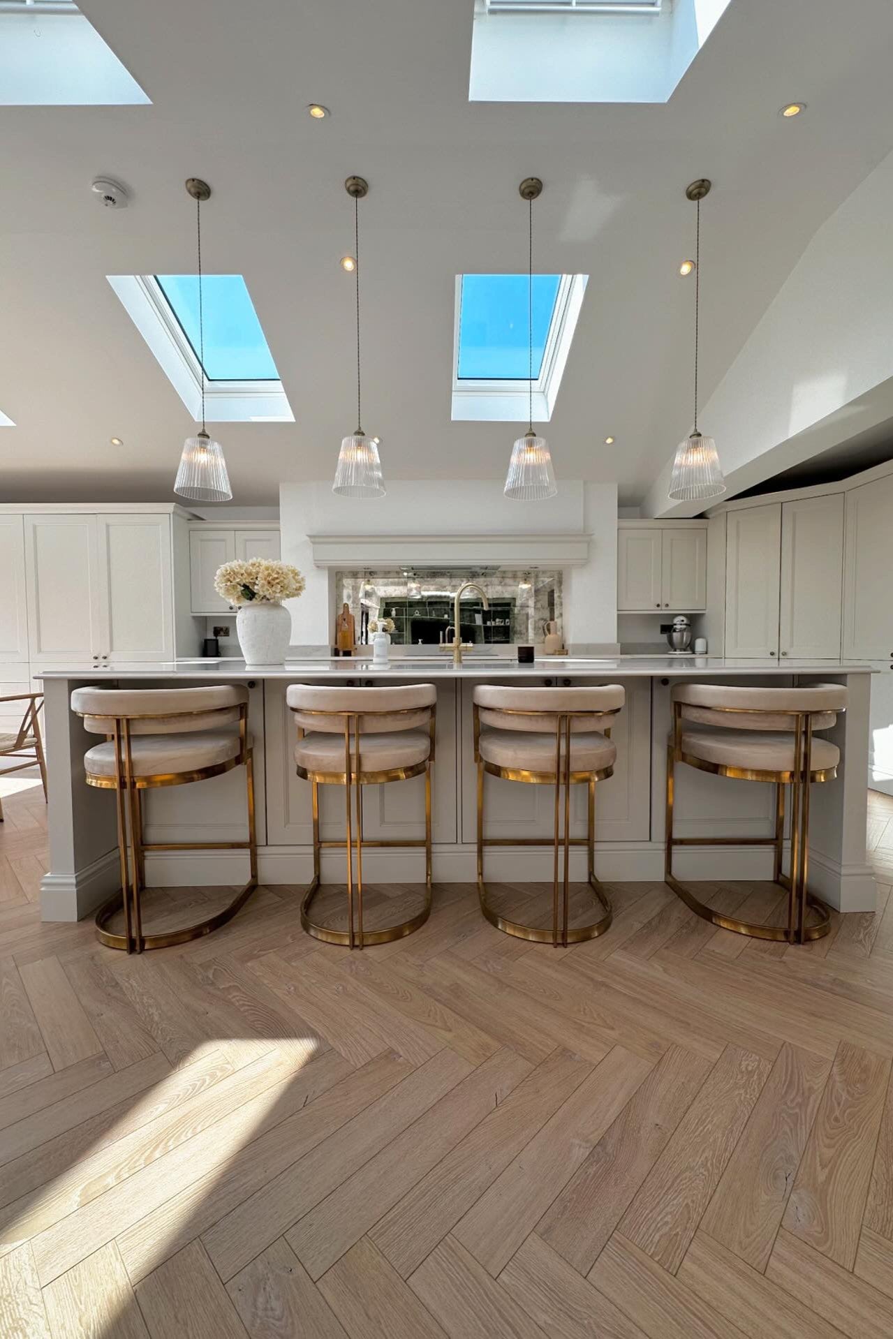 Modern kitchen with skylights, pendant lights, and bar stools.