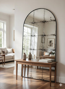 Constantine arch antique mirror leaning in a living room beside a sofa and console table
