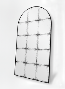 Constantine arch antique mirror at an angle, showing the slim black steel frame and foxed panes