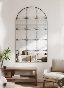 Constantine arch antique mirror hung above a walnut console, reflecting a pale sofa