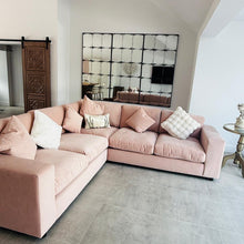 Constantine rectangular antique mirror behind a blush pink sofa on a concrete floor