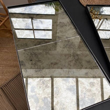 Two panel steel framed antique mirror in a black frame, angled to catch daylight