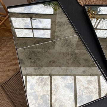 Two panel steel framed antique mirror in a black frame, angled to catch daylight
