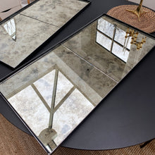 Close detail of the black steel bar dividing two antique mirror panels